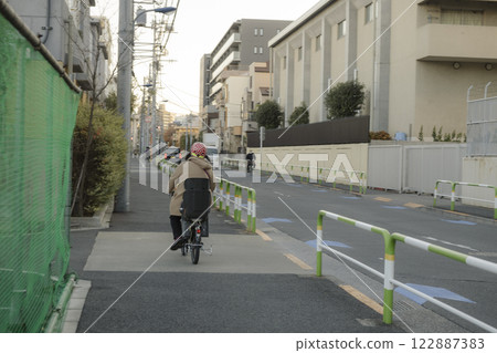 Residential area: Rear view of a man riding a bicycle Residential area: Rear view of a man riding a bicycle 122887383