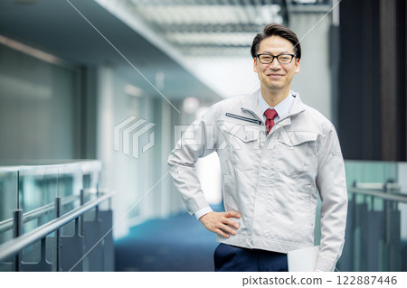 一名身著工作服的男子站在辦公室走廊裡 122887446