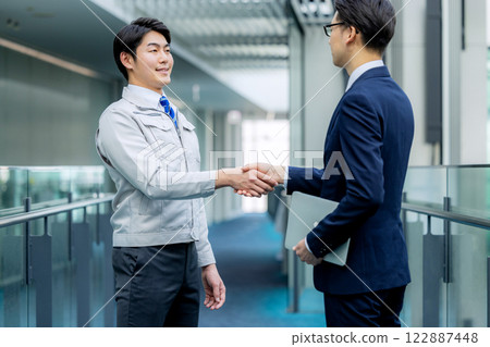 握手：一個穿工作服的男人和一個穿西裝的男人 122887448