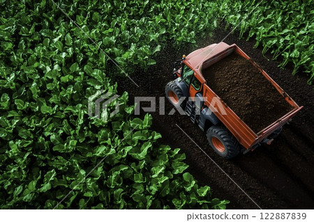 Agricultural Vehicle Spreading Organic Material in Green Field 122887839