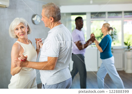 Senior woman practicing samba with man during dance class Senior woman practicing samba with man during dance class 122888399