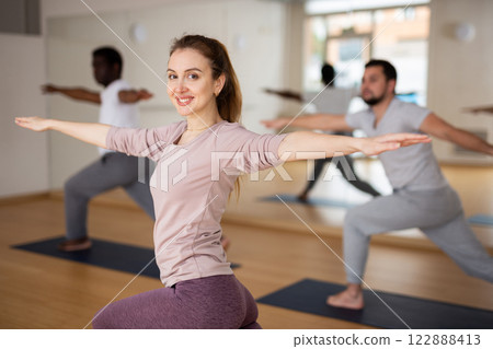 Woman practising warrior II pose in gym Woman practising warrior II pose in gym 122888413