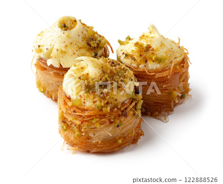 Delicious traditional dessert made with shredded pastry filled with cream and topped with pistachios in a sweet syrup Delicious traditional dessert made with shredded pastry filled with cream and topped with pistachios in a sweet syrup 122888526