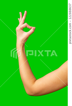 Hand gesture representing approval against a bright green background during a creative project 122888637