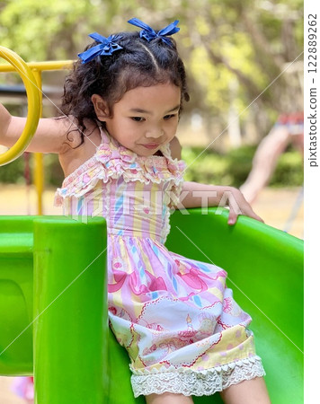 Asian little girl playing on slide in the Playground in Thailand Asian little girl playing on slide in the Playground in Thailand 122889262