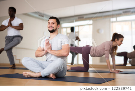 Young bearded man sitting in Padmasana with hands clasped in namaste 122889741