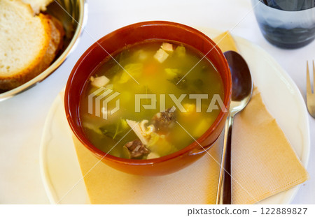Escudella barrejada soup is poured in deep clay bowl - cooked according to old Catalan recipe Escudella barrejada soup is poured in deep clay bowl - cooked according to old Catalan recipe 122889827