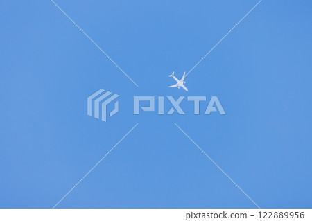 A white plane flying in a clear, blue sky without clouds 122889956