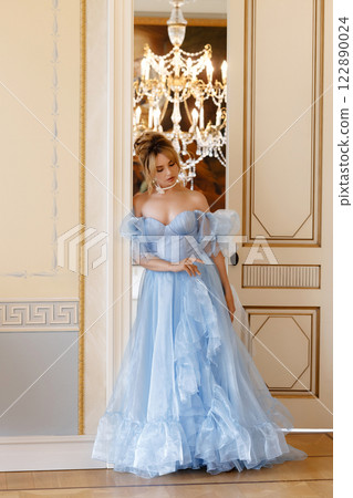 Elegant woman in a light blue ball gown in a luxurious classic interior 122890024