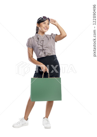 Portrait of an Asian Indonesian woman with sunglasses carrying a shopping bag isolated over a white background. Copy space or mockup. Concept of shopping, lifestyle, or consumerism 122890496