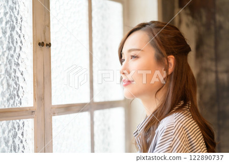 A woman standing by the window A woman standing by the window 122890737