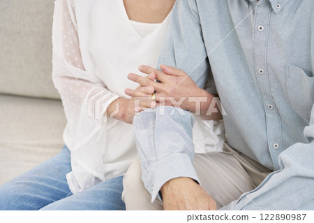 Senior couple with arms folded, living room, no faces Senior couple with arms folded, living room, no faces 122890987