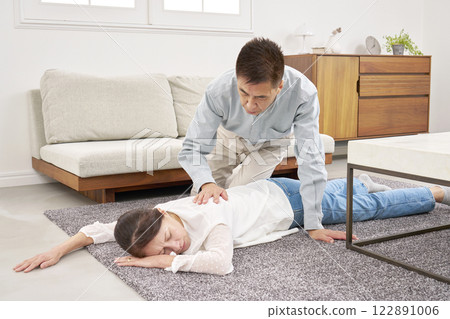 Senior woman suddenly falls ill in the living room 122891006