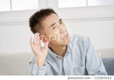 Hearing-impaired senior man living room Hearing-impaired senior man living room 122891018