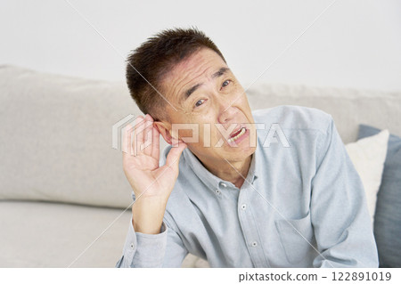 Hearing-impaired senior man living room Hearing-impaired senior man living room 122891019