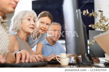 Old woman learning computer programs with teacher in training room Old woman learning computer programs with teacher in training room 122892450