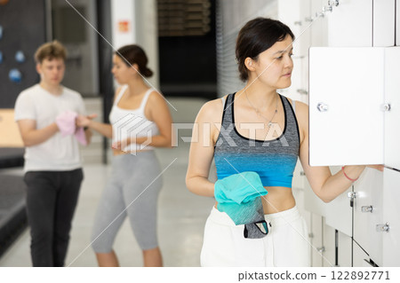 Young asian woman putting things in locker in locker room Young asian woman putting things in locker in locker room 122892771