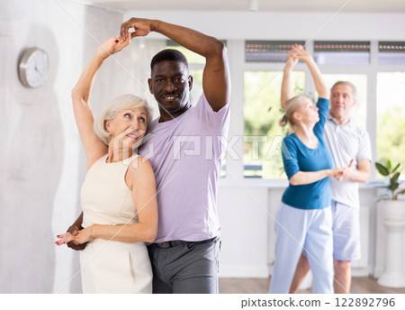 Mature men and women practicing Ballroom dances in training room Mature men and women practicing Ballroom dances in training room 122892796