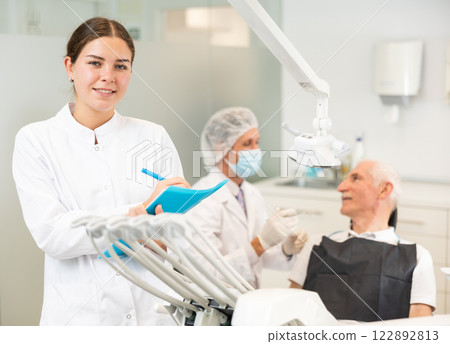 Young woman nurse with paper is standing in dental office, clinic 122892813