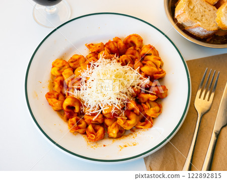 Tortellini with tomatoes, tomato gravy amound of grated parmesan cheese is placed in center of dish Tortellini with tomatoes, tomato gravy amound of grated parmesan cheese is placed in center of dish 122892815