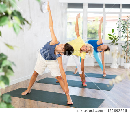 Preteen boy practicing side angle pose of yoga in light fitness room 122892816