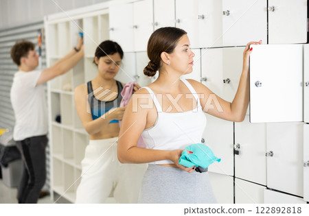 Young woman putting things in locker in locker room 122892818