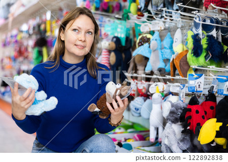 Confident female customer picking out toys for pets in pet store Confident female customer picking out toys for pets in pet store 122892838