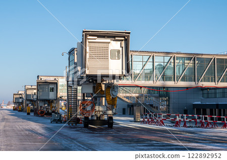 Empty passenger boarding bridges at airport apron at winter Empty passenger boarding bridges at airport apron at winter 122892952