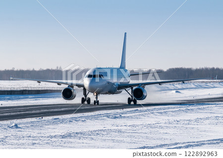 White passenger airliner taxiing on taxiway in snowy winter day White passenger airliner taxiing on taxiway in snowy winter day 122892963
