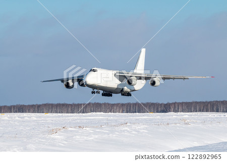 White wide body transport cargo aircraft approaches for landing at winter airport White wide body transport cargo aircraft approaches for landing at winter airport 122892965
