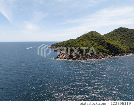 Rocky coastline and lush green hills meeting the vibrant blue sea under a bright clear sky. Koh Tao, Thailand. 122896319
