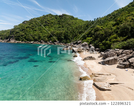 Scenic coastline featuring lush green hills meeting the turquoise sea under a bright sky. Koh Tao, Thailand. 122896321