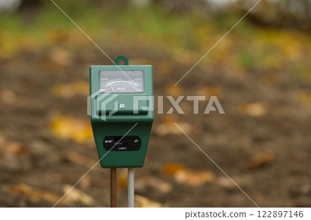 Close-up of a soil moisture and pH meter in a garden setting to monitor plant care conditions 122897146