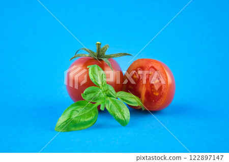 Cherry tomatoes with basil leaves over a blue 122897147