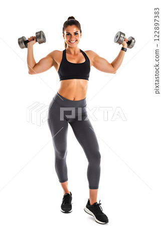 Fitness enthusiast performs strength training with dumbbells in a bright studio environment 122897383