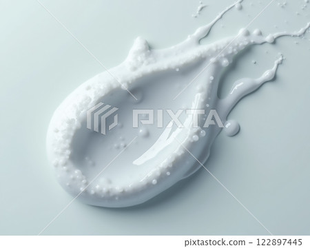 Droplet of white liquid on smooth surface with splashes and reflections reflecting natural lighting 122897445