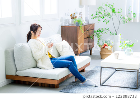 Woman sitting on a sofa and looking at a smartphone 122898738