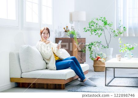 Woman sitting on a sofa and looking at a smartphone 122898746