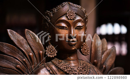 A statue of a woman with a gold face and gold earrings 122898980