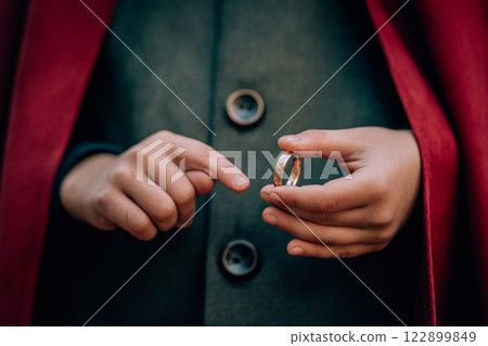 Hands of boy cosplayer in hobbit cape costume holding and wants to wear golden ring. Fantasy journey 122899849