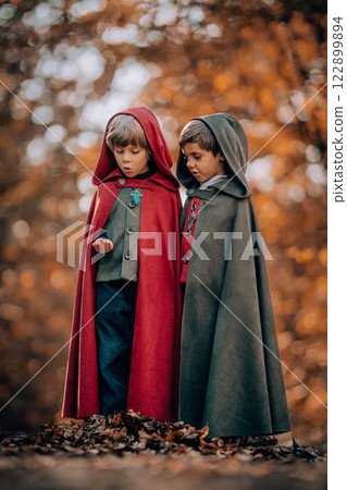Hobbits boys in cape costumes standing in autumn forest with ring. Fantasy journey, halloween 122899894