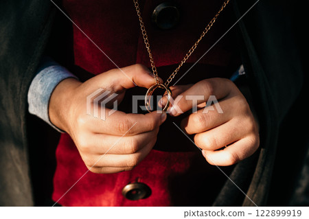 Unrecognizable child cosplayer in hobbit cape costume holding and wants to wear golden ring. Fantasy Unrecognizable child cosplayer in hobbit cape costume holding and wants to wear golden ring. Fantasy 122899919