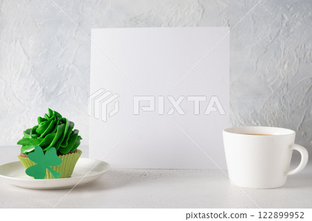 Patrick's Day empty blank and cupcake with green whipped cream decorated shamrock on white background. Festive template for recipe or menu. Copy space. 122899952