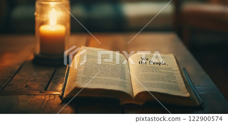 Open book showing we the people with candle on wooden table celebrating president's day 122900574