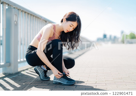 綁鞋帶的運動服的女人 122901471