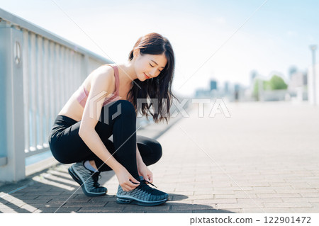 綁鞋帶的運動服的女人 122901472