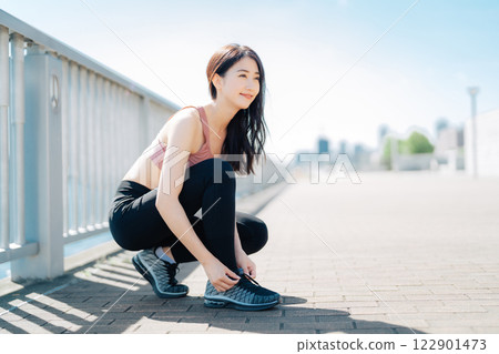 綁鞋帶的運動服的女人 122901473