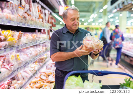 Mature man choosing packaged piece of meat in grocery store 122901523