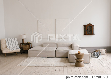 Scandinavian modern minimalistic living room with grey couch and armchair. Small table with lamp and toy car is on the floor 122901651