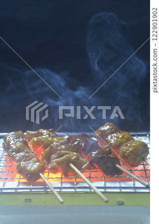 Grilling yakitori on a charcoal grill with rising smoke Grilling yakitori on a charcoal grill with rising smoke 122901902